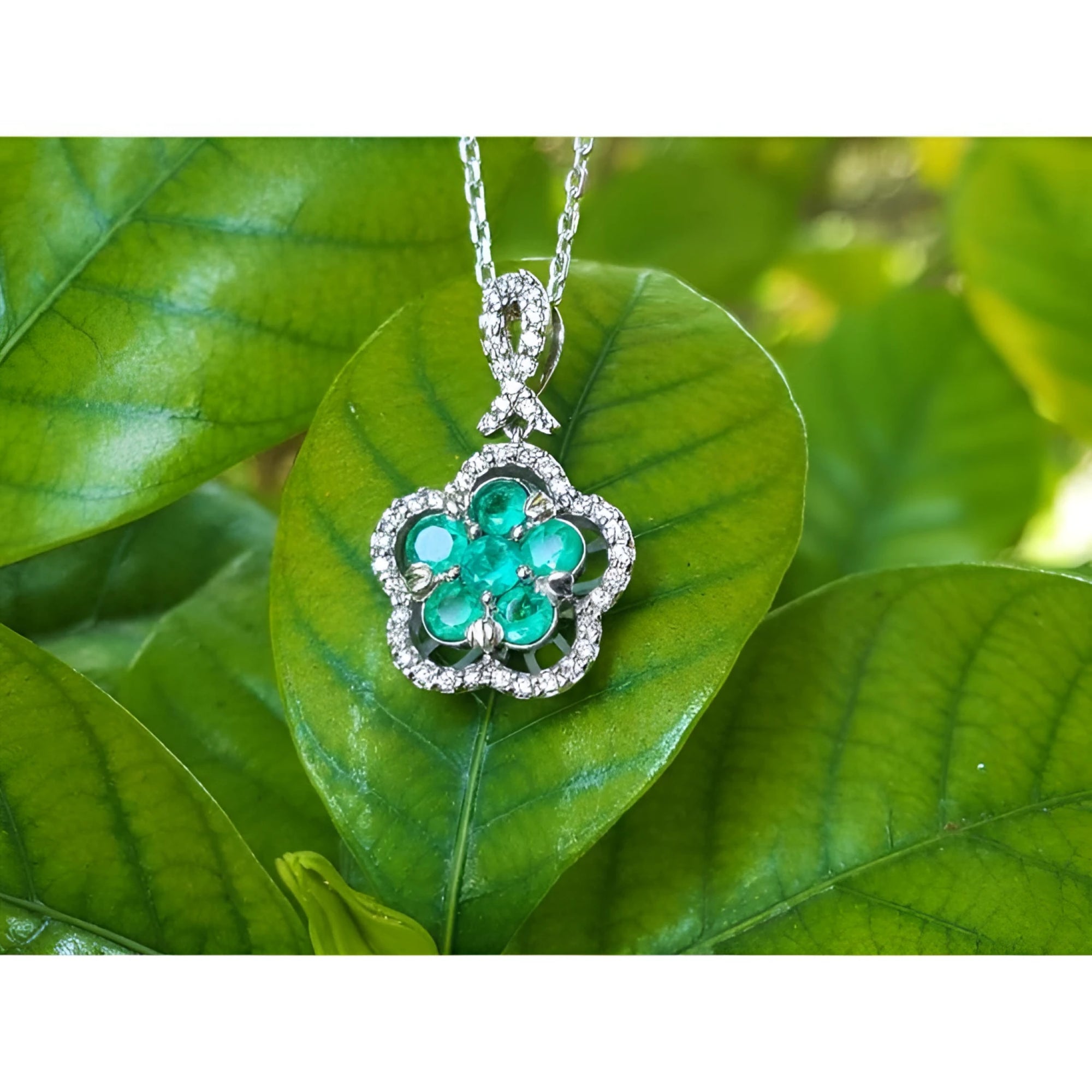 Emerald cluster necklace with round cut emeralds and diamonds in 14K white gold, clover-like design.