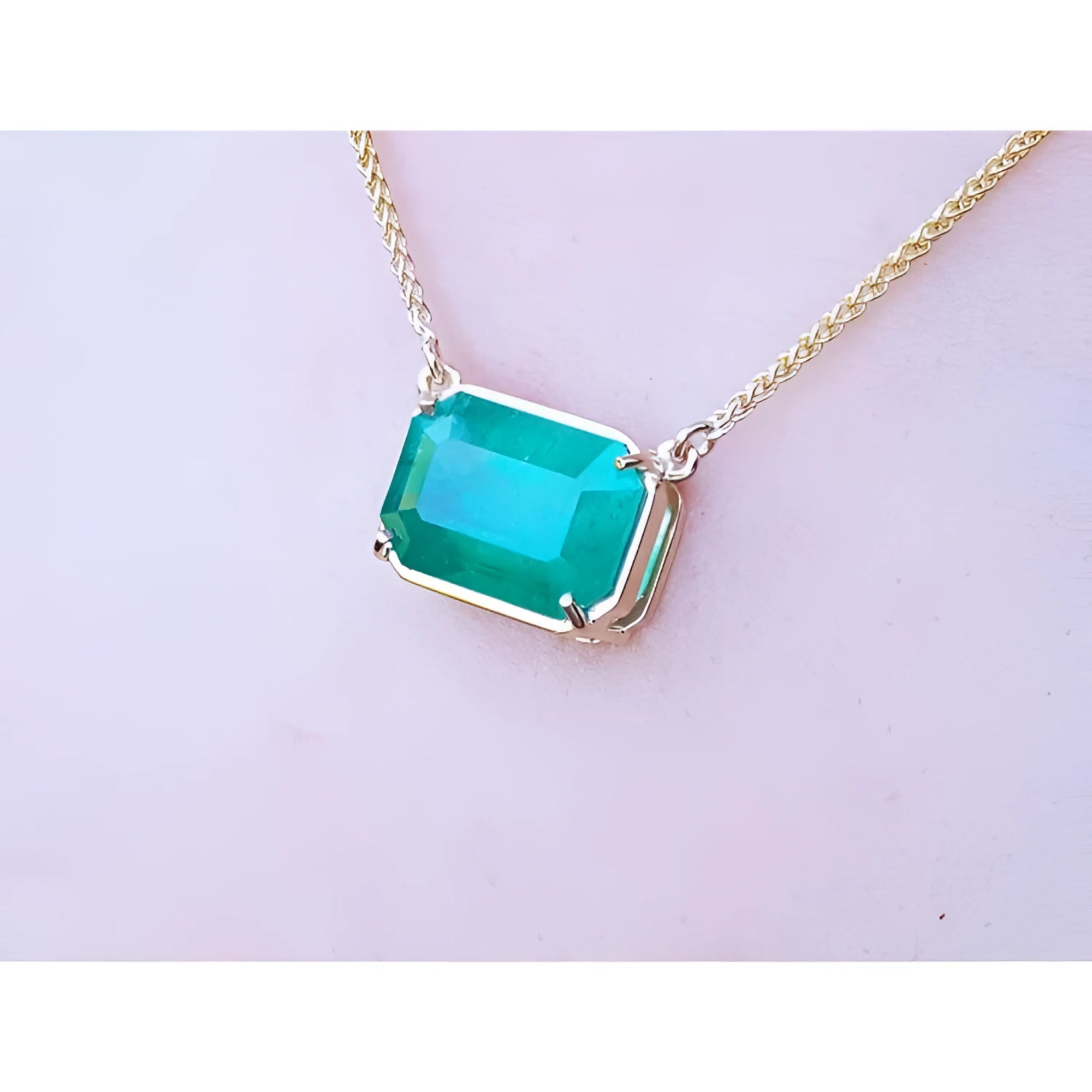 Emerald-cut Colombian emerald solitaire necklace in 18K yellow gold.