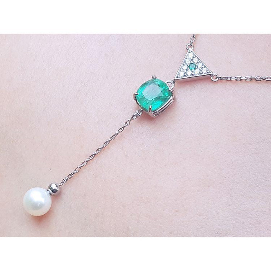14K white gold necklace with cushion-cut emerald, diamond triangle cluster, and dangling freshwater pearl.