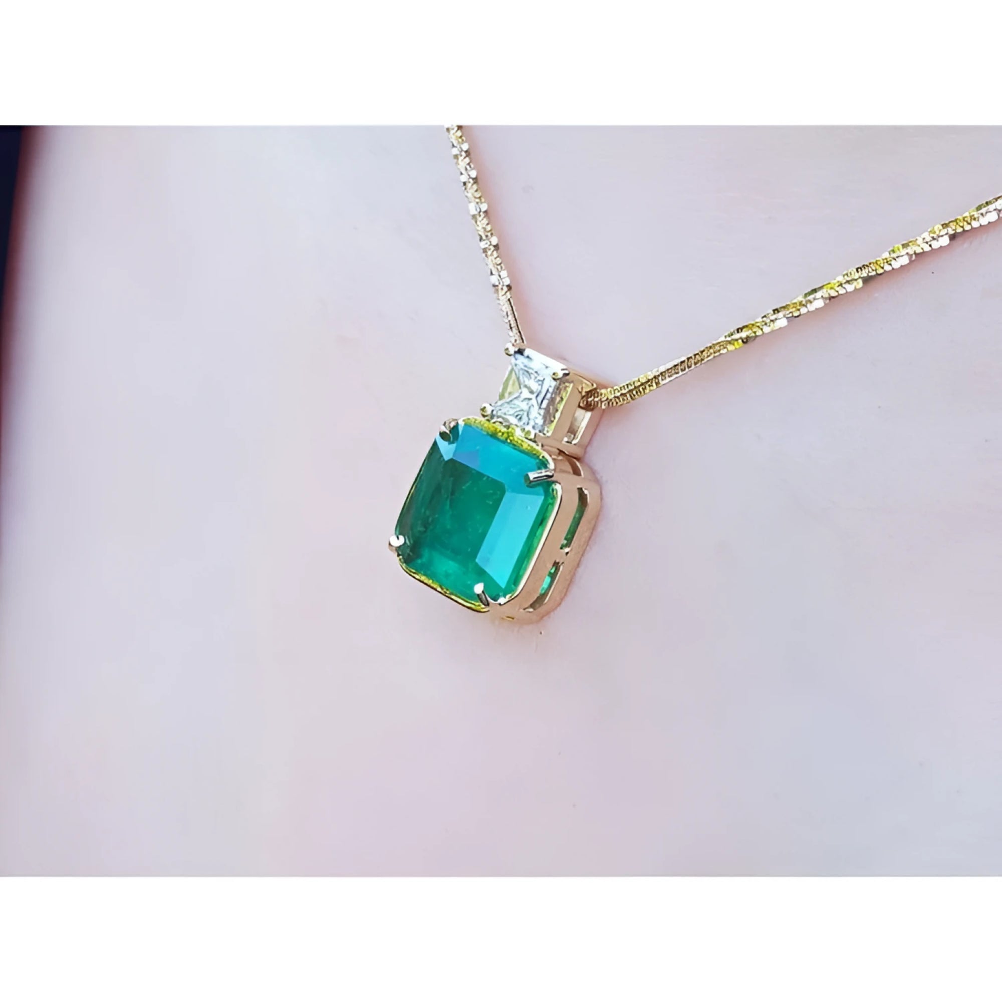 Asscher cut Colombian emerald and princess cut diamond 18K yellow gold necklace on a person.