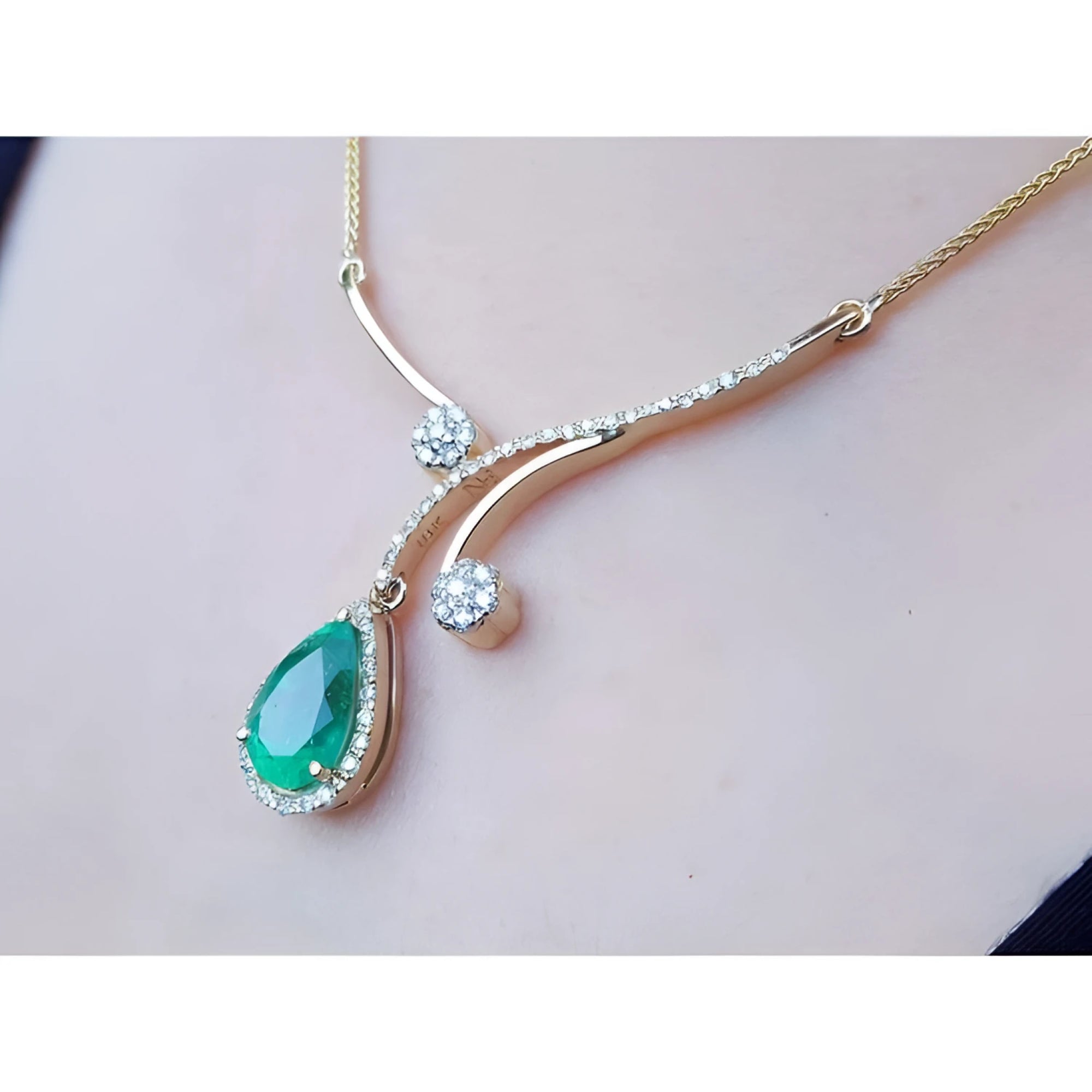 Colombian pear emerald necklace with diamonds in 18K yellow gold, worn on a person.