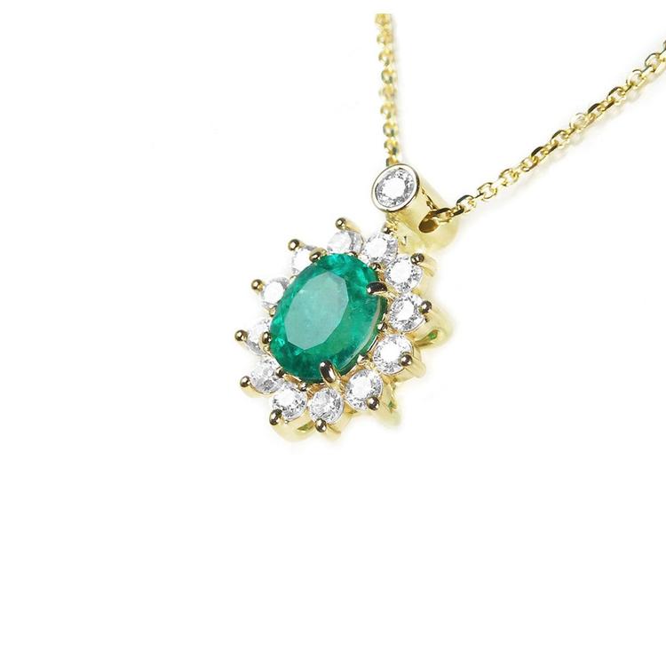 Left side view of a yellow gold necklace with a natural emerald gemstone in a halo diamond on a white background