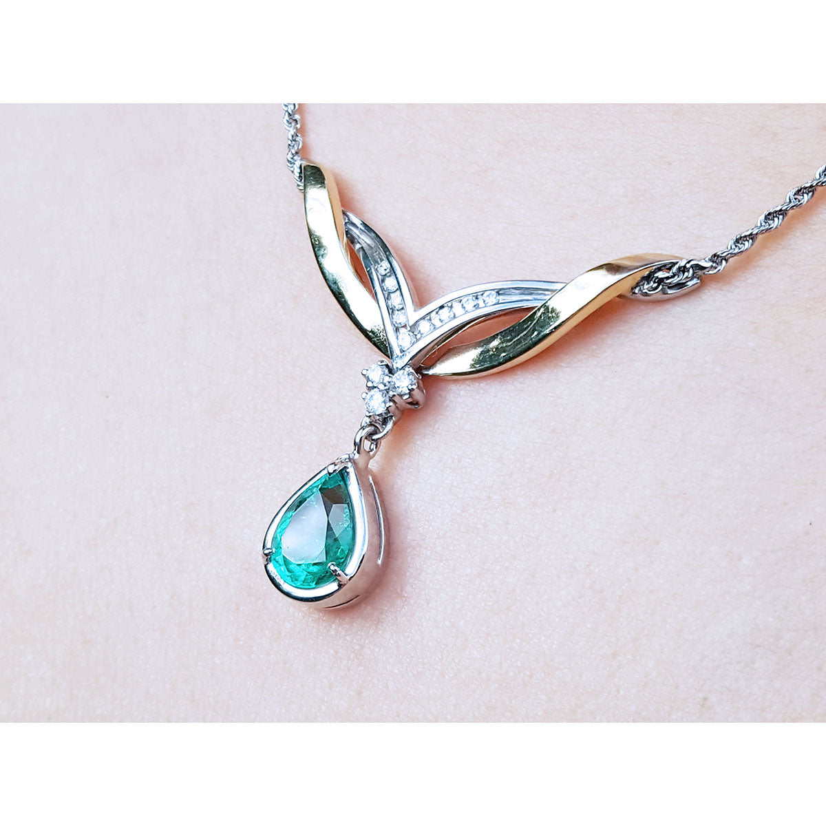 A left side jewelry necklace with a dangling teardrop emerald gemstone solitaire pendant on woman&#39;s collar