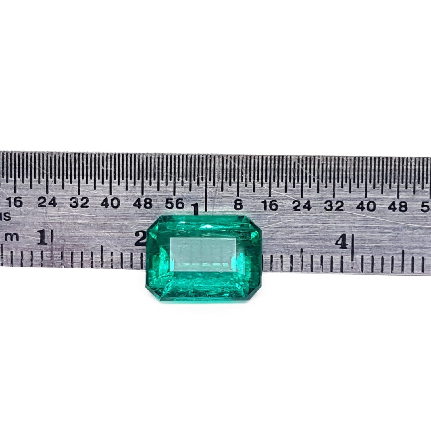 Vibrant bluish-green 4.18 carat emerald-cut loose emerald from Muzo, Colombia, next to a ruler.