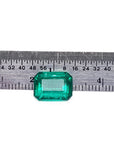 Vibrant bluish-green 4.18 carat emerald-cut loose emerald from Muzo, Colombia, next to a ruler.