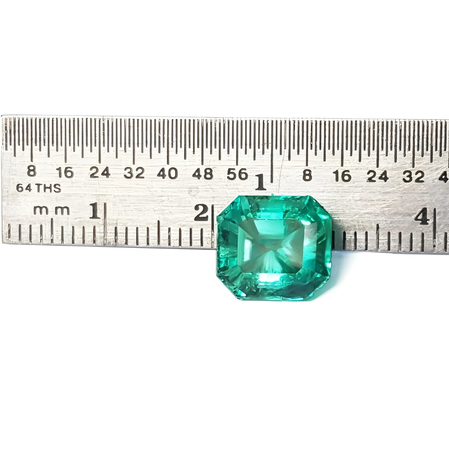 4.71 carat emerald-cut Colombian emerald, medium bluish-green, next to a ruler for scale.