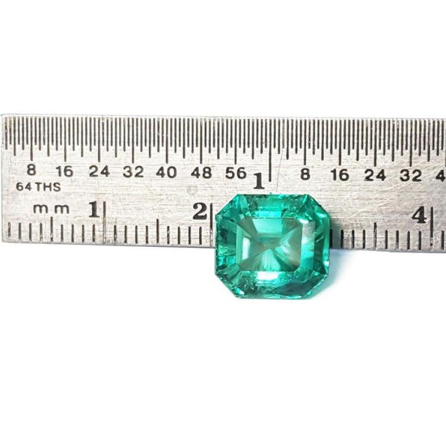 4.71 carat emerald-cut Colombian emerald, medium bluish-green, next to a ruler for scale.