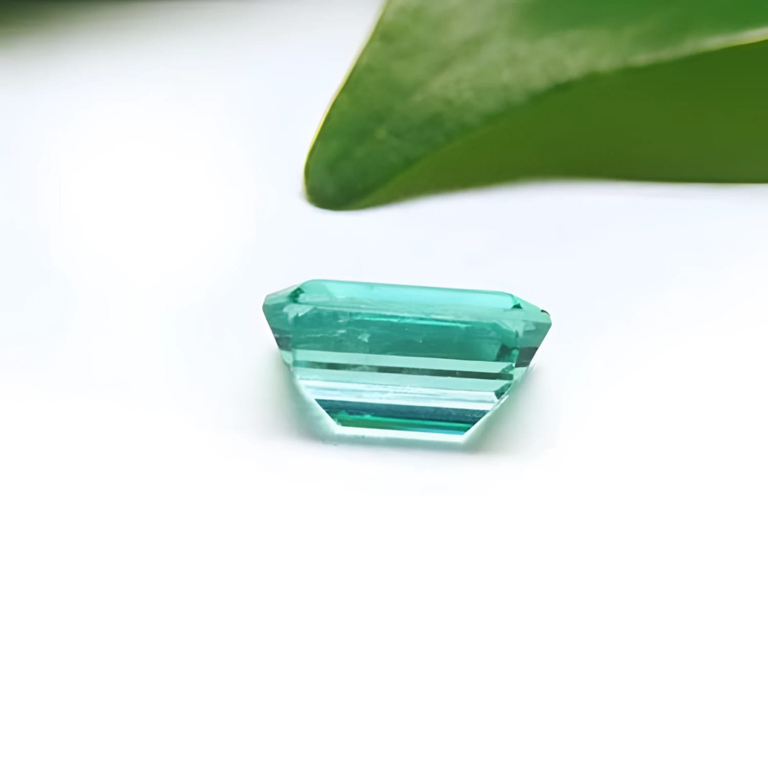 1.83 carat emerald-cut Colombian emerald with a vibrant bluish-green hue on a white background.