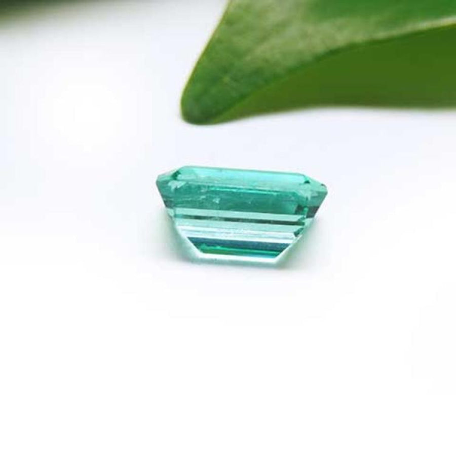 1.83 carat emerald-cut Colombian emerald with a vibrant bluish-green hue on a white background.