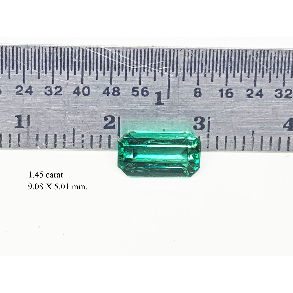 Emerald cut emerald stone with measurements on a ruler