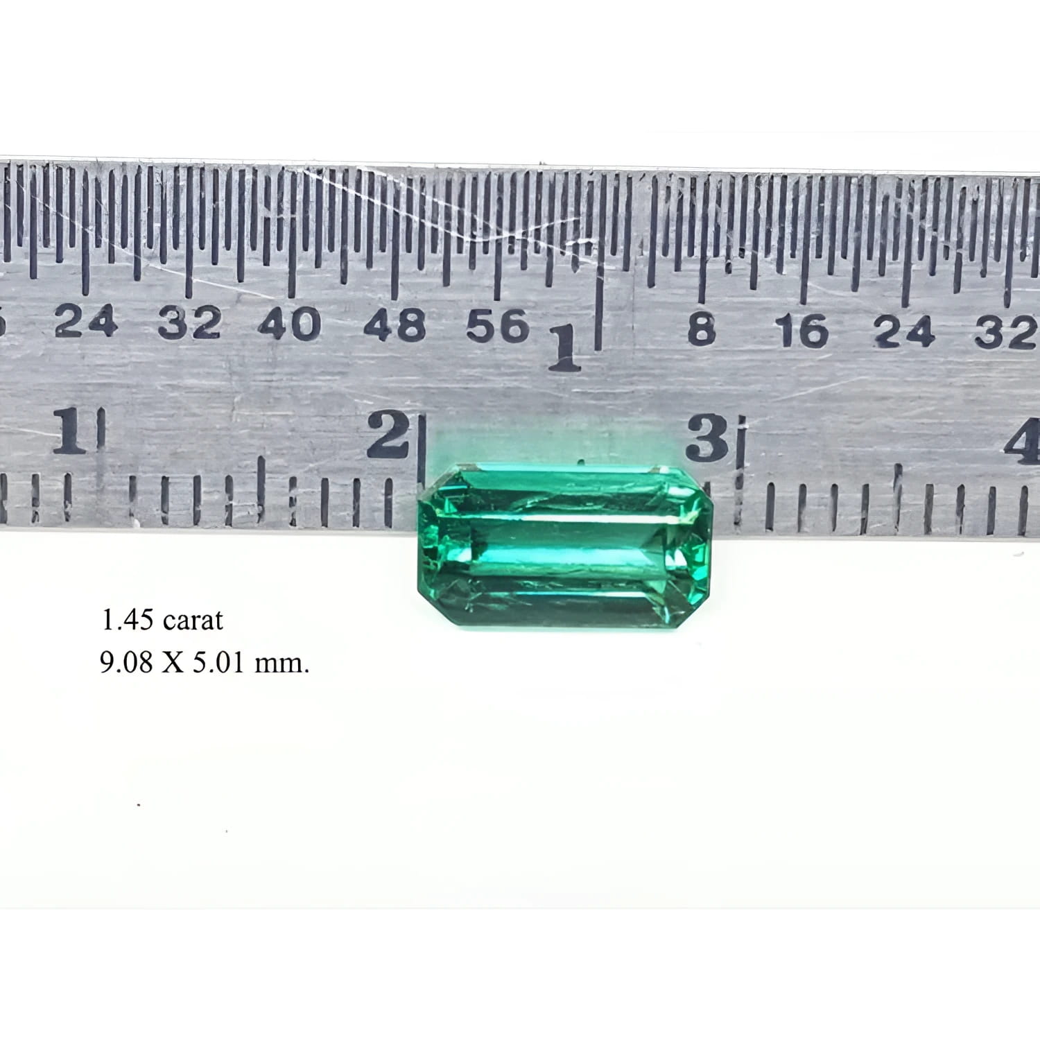 1.45 carat emerald gemstone, 9.08 X 5.01 mm, shown with a ruler for scale.