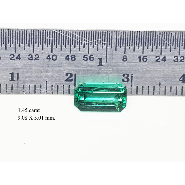 Emerald cut emerald stone with measurements on a ruler