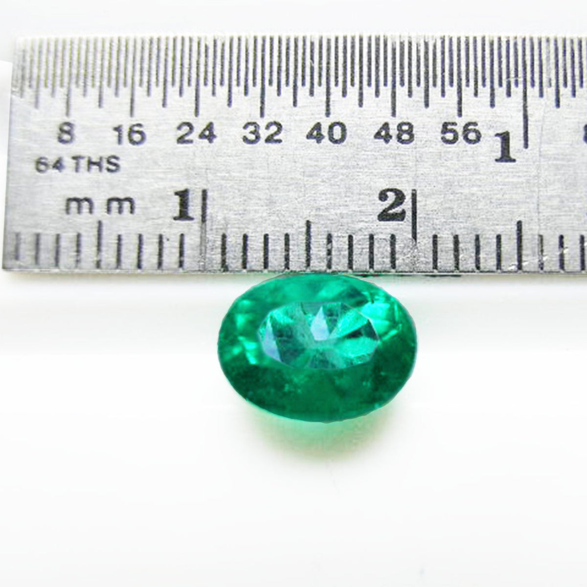 Natural loose Colombian emerald oval cut, next to a ruler for measuring size