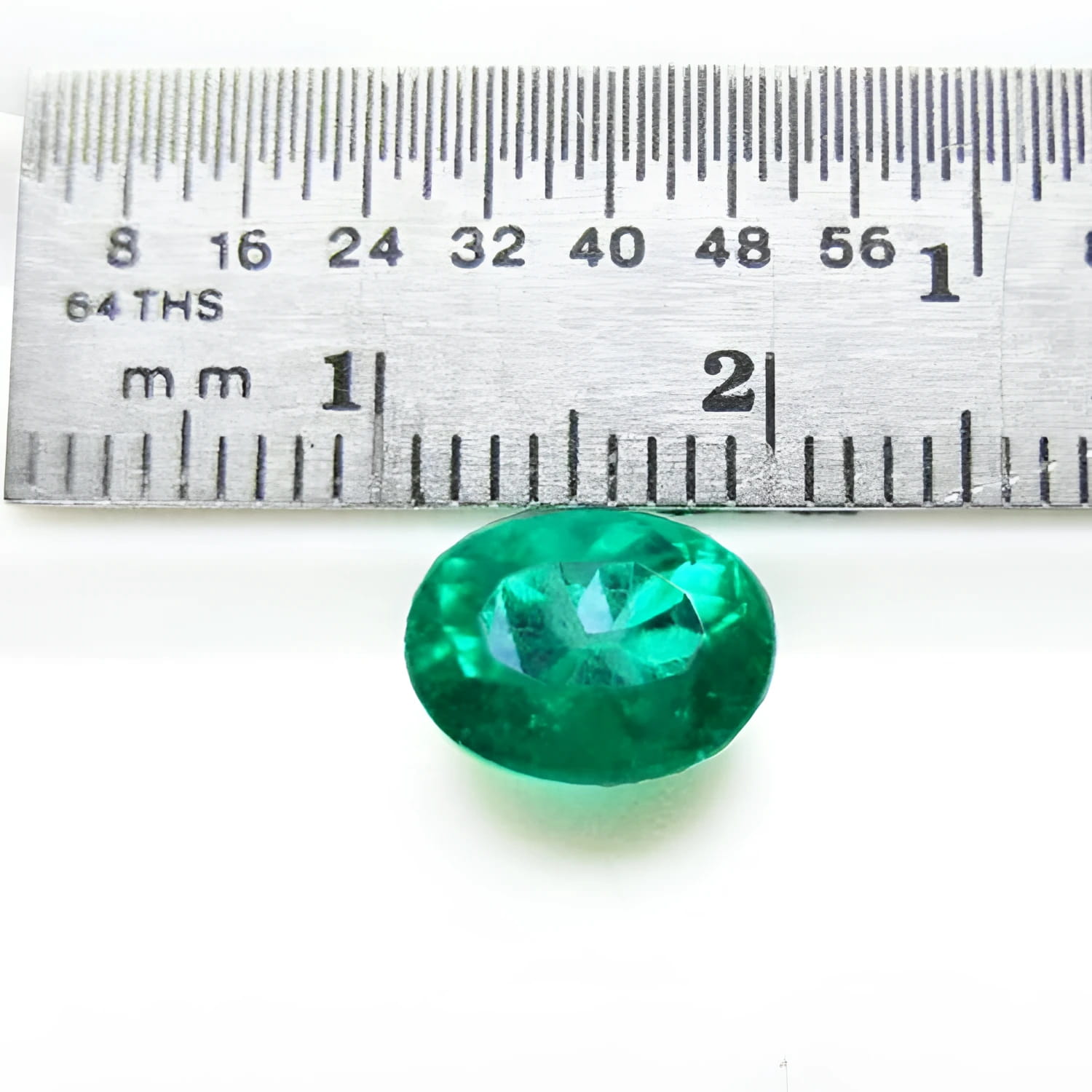 2.11 ct oval cut deep bluish-green Colombian emerald next to a ruler for scale.