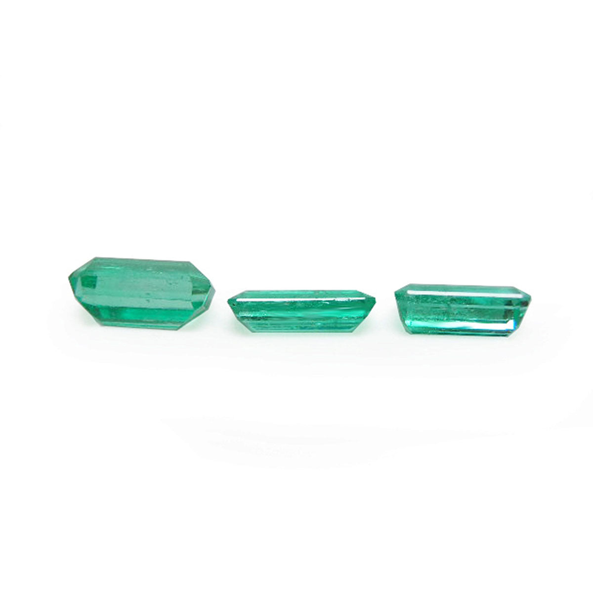 Loose emeralds matched trio set for earrings and pendant, undersides girdles and pavilions visibles