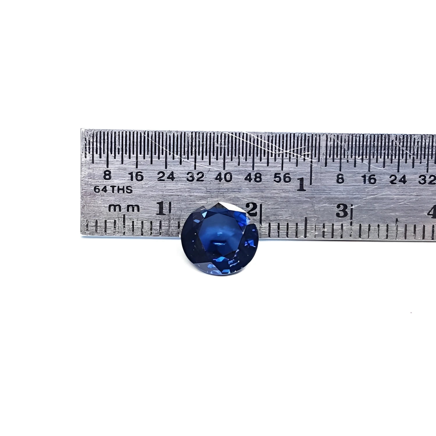 2.39 ct. loose round natural deep blue sapphire from Sri Lanka, shown with a ruler for scale.
