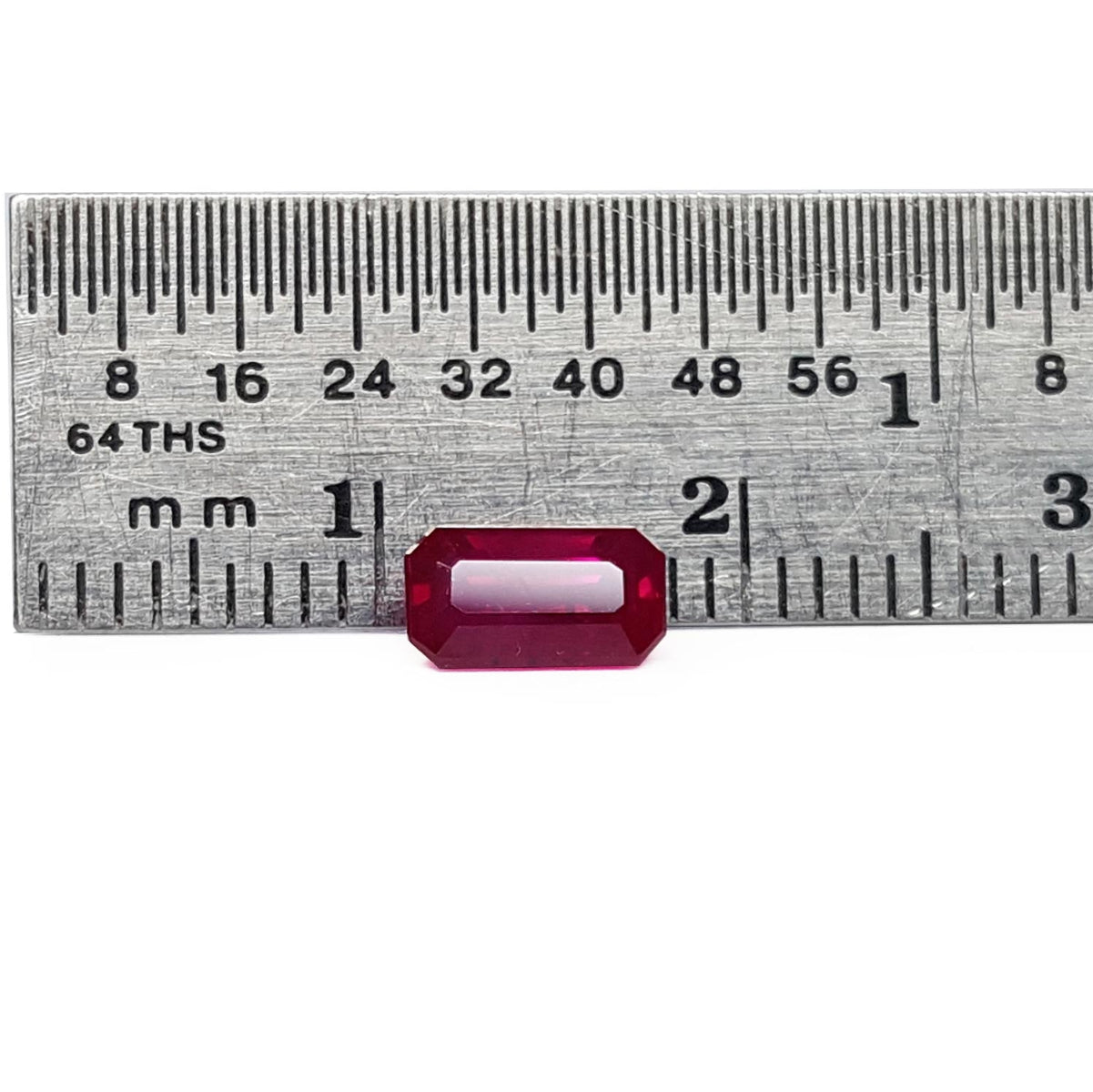 loose natural ruby emerald cut from Burma, on a ruler for scale