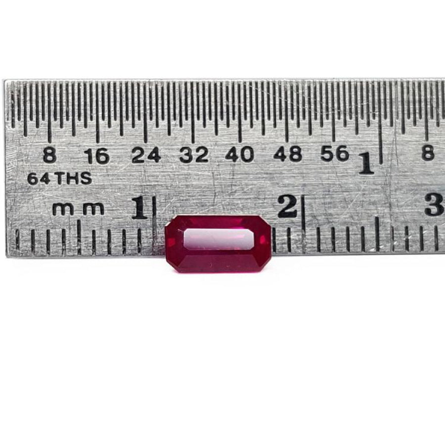 0.94 carat natural Burma ruby, emerald cut, vibrant red, displayed on a ruler.