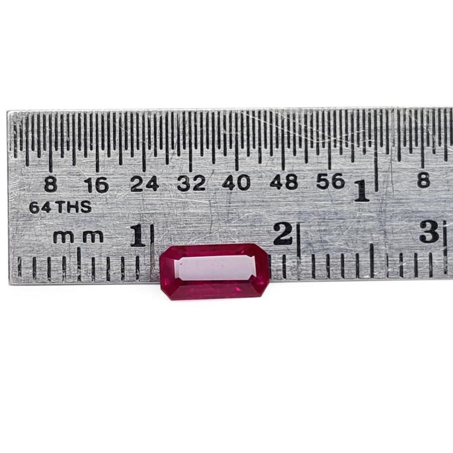 Sparkling 0.97 carat medium deep rich red emerald cut natural Burma loose ruby next to a ruler.