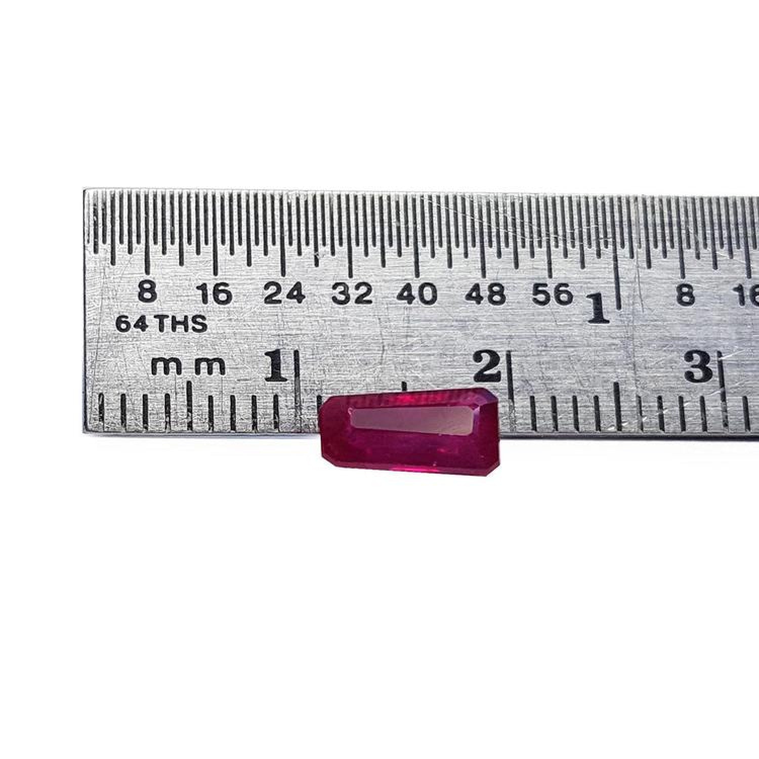 Deep red 1.07 ct. natural loose Burma ruby, tapered baguette cut, next to a ruler.