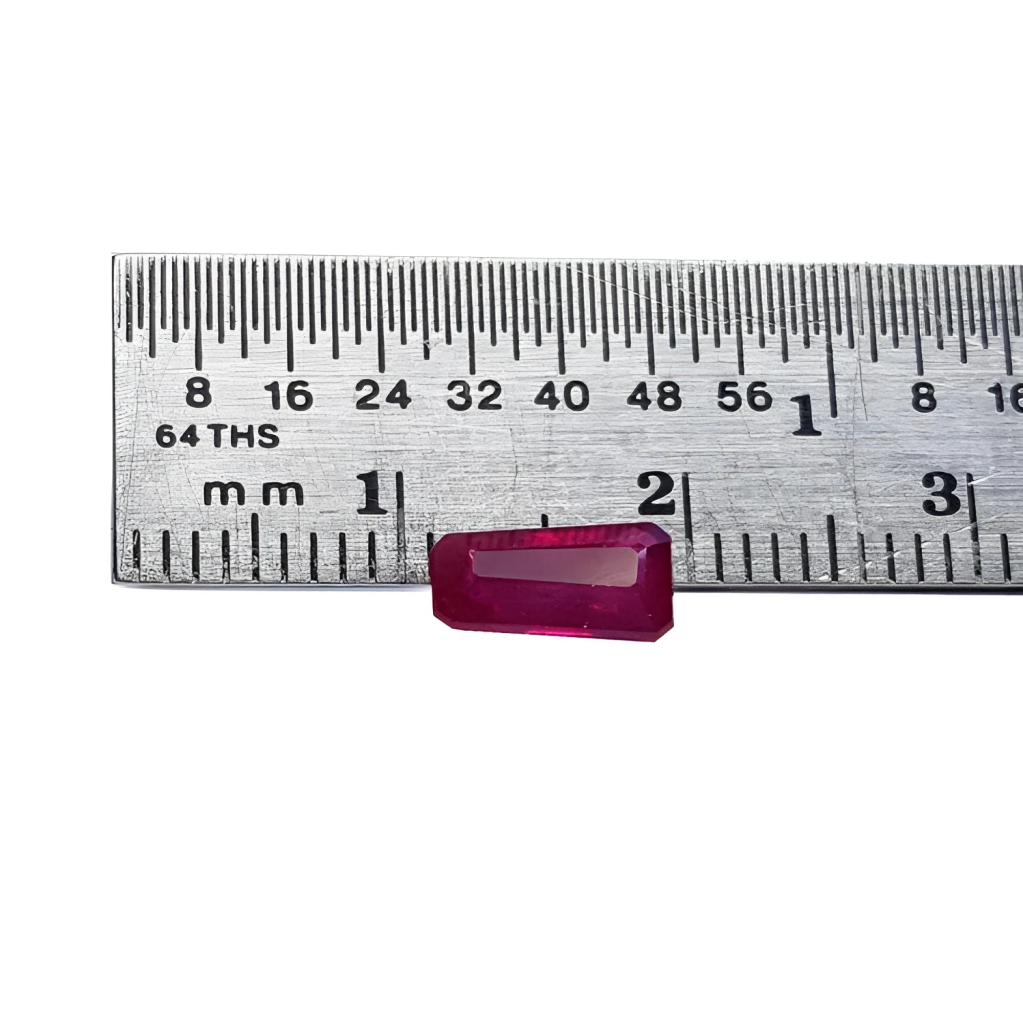 Deep red 1.07 ct. natural loose Burma ruby, tapered baguette cut, next to a ruler.