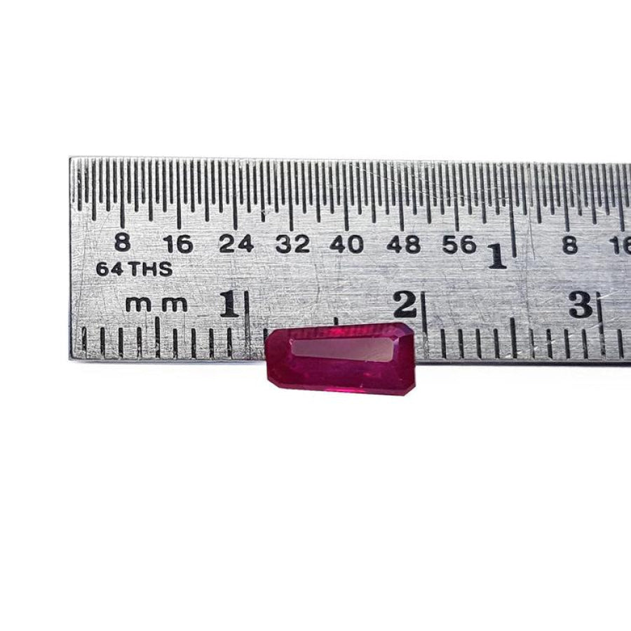 Deep red 1.07 ct. natural loose Burma ruby, tapered baguette cut, next to a ruler.