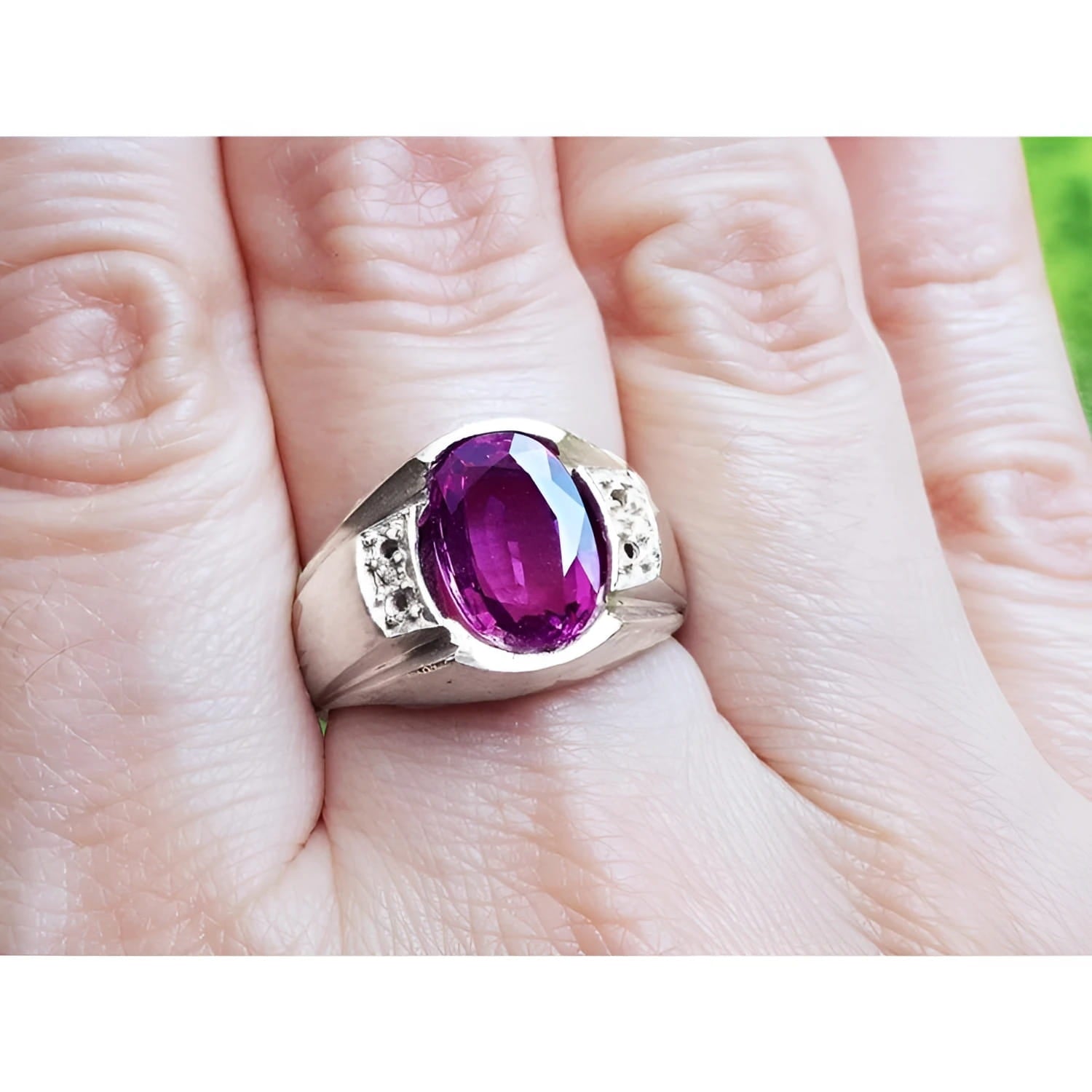 Oval-cut natural pink sapphire ring with sparkling medium pink stone and white accents on a hand.