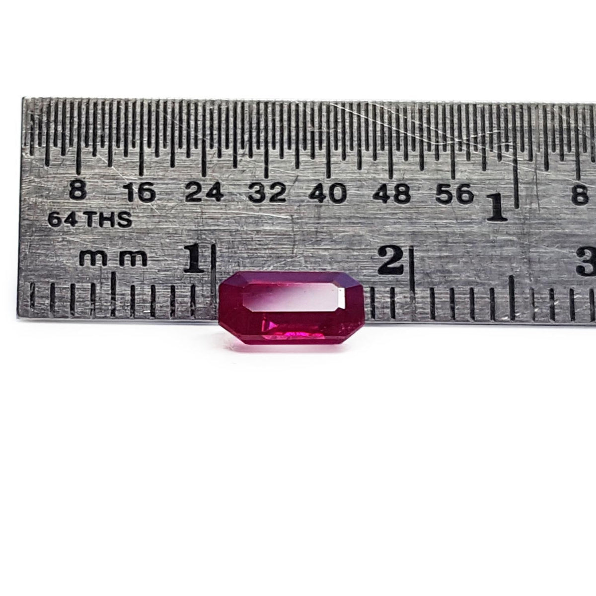 Loose ruby Burma natural gemstone emerald cut, on a ruler for scale