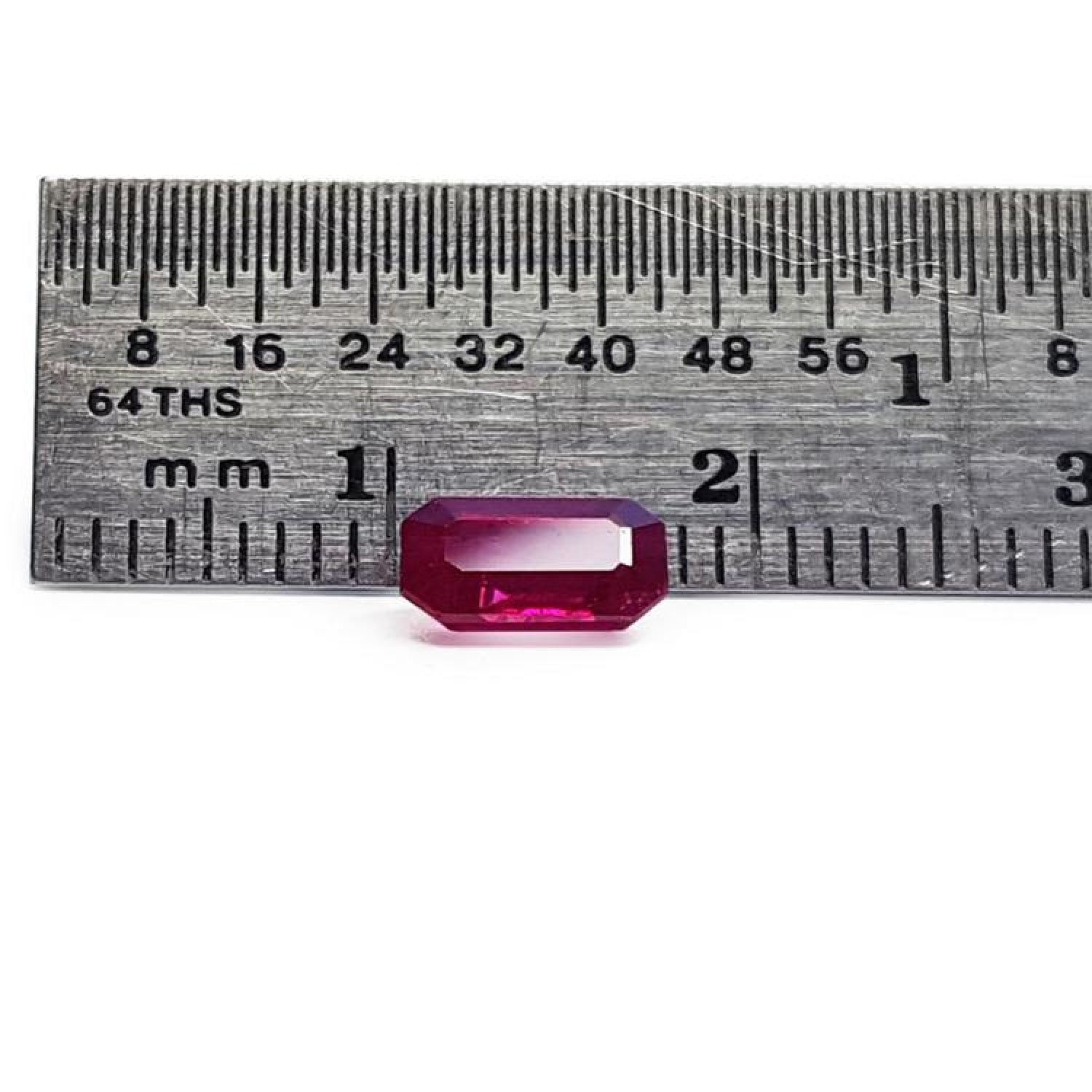 0.95 carat natural Burma ruby, emerald cut, displayed next to a ruler for scale.