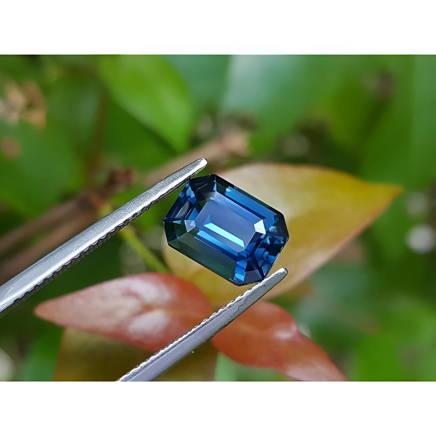 3.53 ct GIA certified natural greenish-blue sapphire, rectangular emerald cut, held by tweezers.