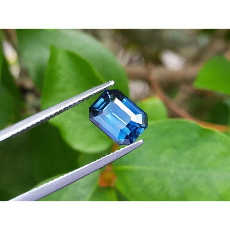 3.53 ct GIA certified natural greenish-blue sapphire, rectangular emerald cut, held by tweezers.