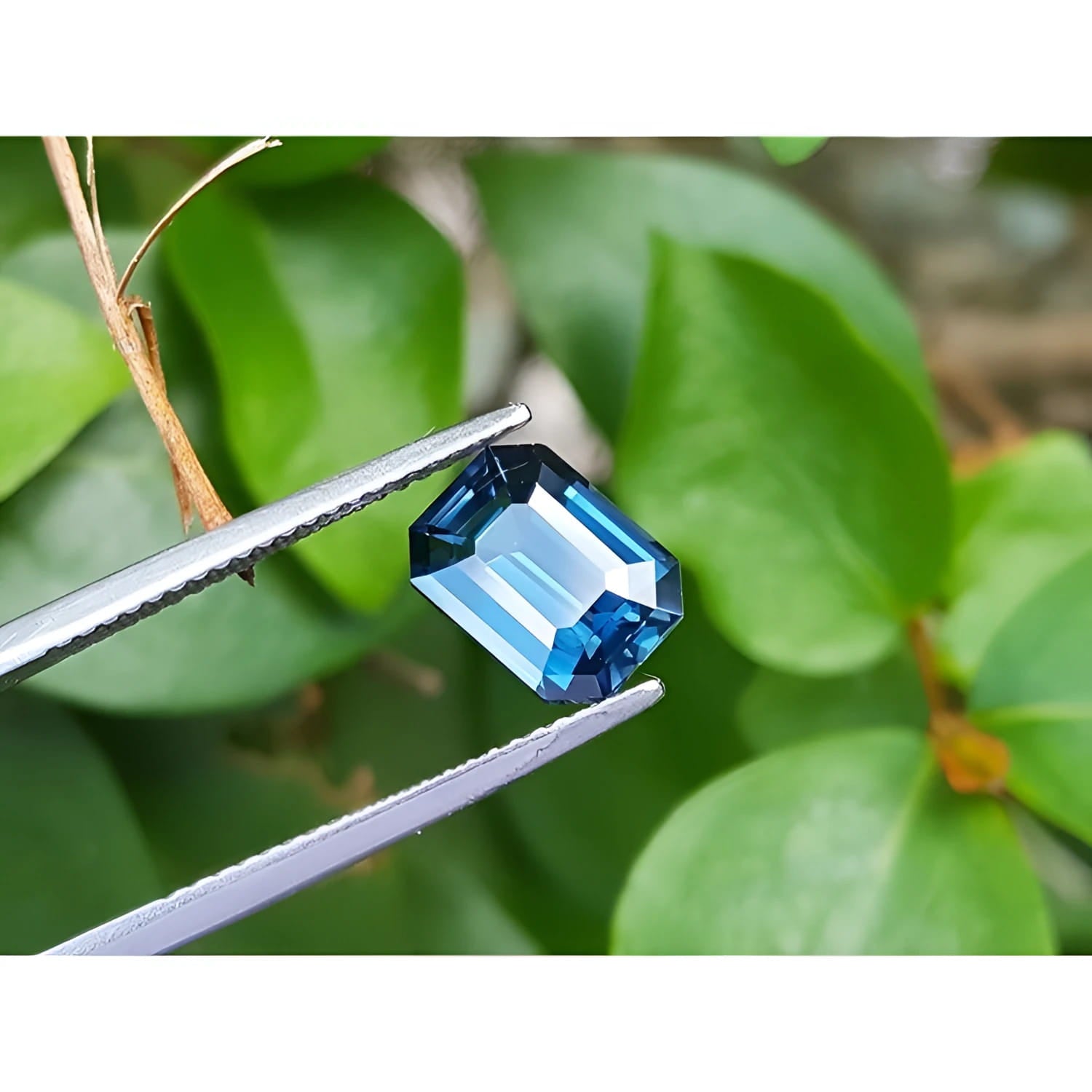 3.53 ct GIA-certified natural greenish-blue sapphire, rectangular emerald cut, held by tweezers.