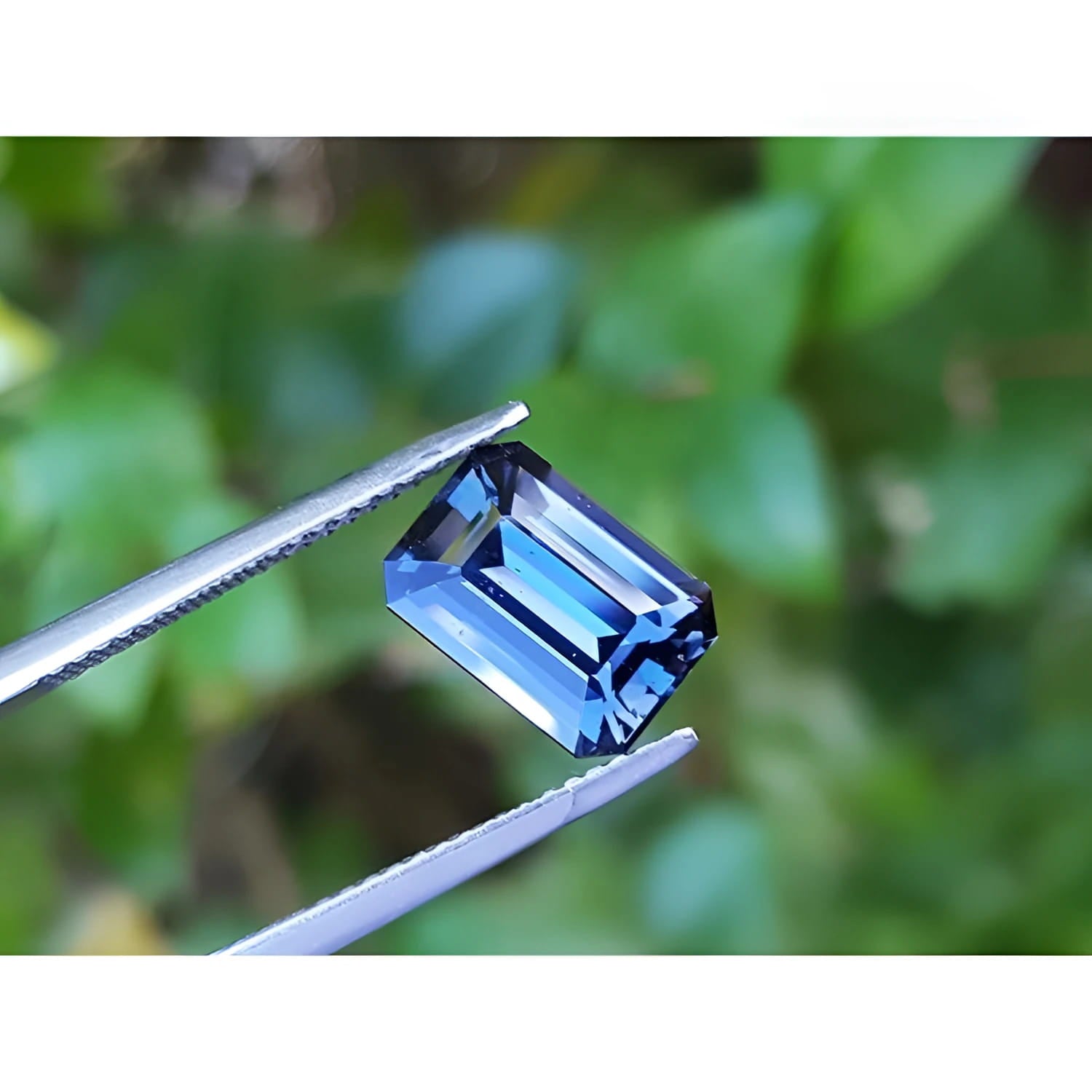 3.90 ct untreated GIA certified blue changing sapphire, rectangular emerald-cut, held by tweezers.