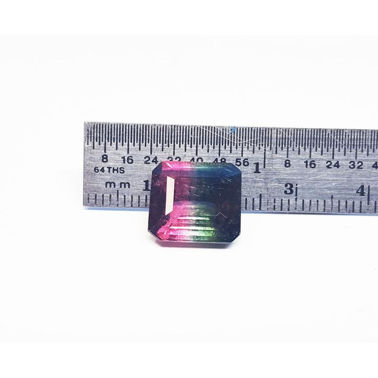 7.75 ct. emerald-cut Brazilian watermelon tourmaline, vibrant red-orange to deep bluish-green, next to a ruler.