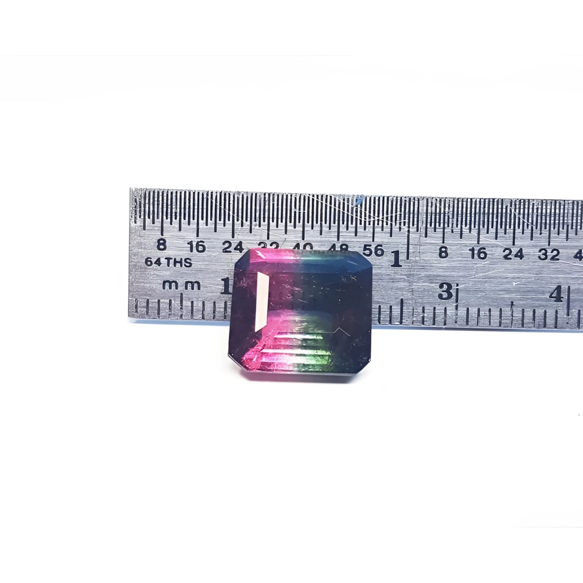 7.75 ct. emerald-cut Brazilian watermelon tourmaline, vibrant red-orange to deep bluish-green, next to a ruler.