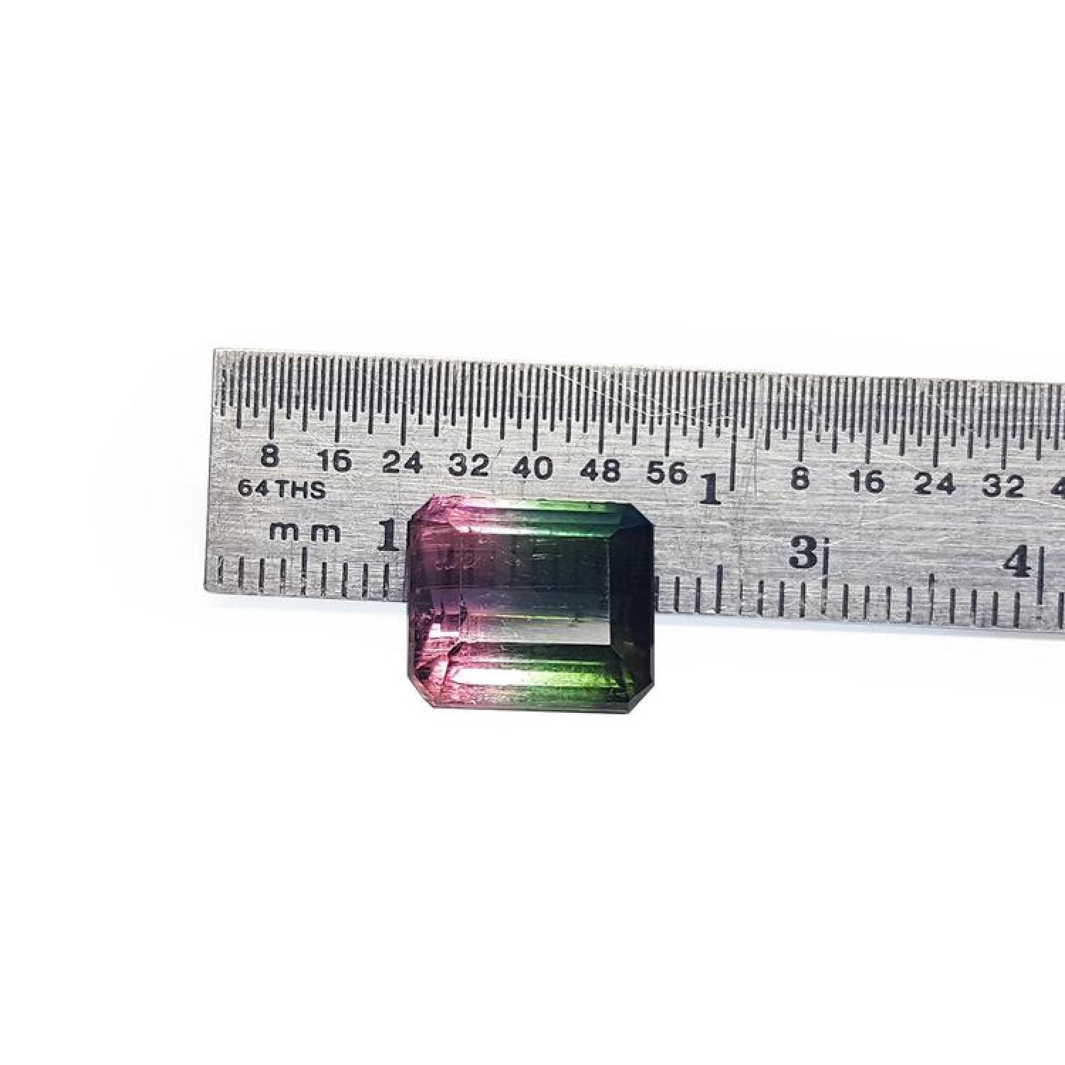 Loose 6.55 ct. emerald-cut watermelon tourmaline, red to green, next to a ruler.