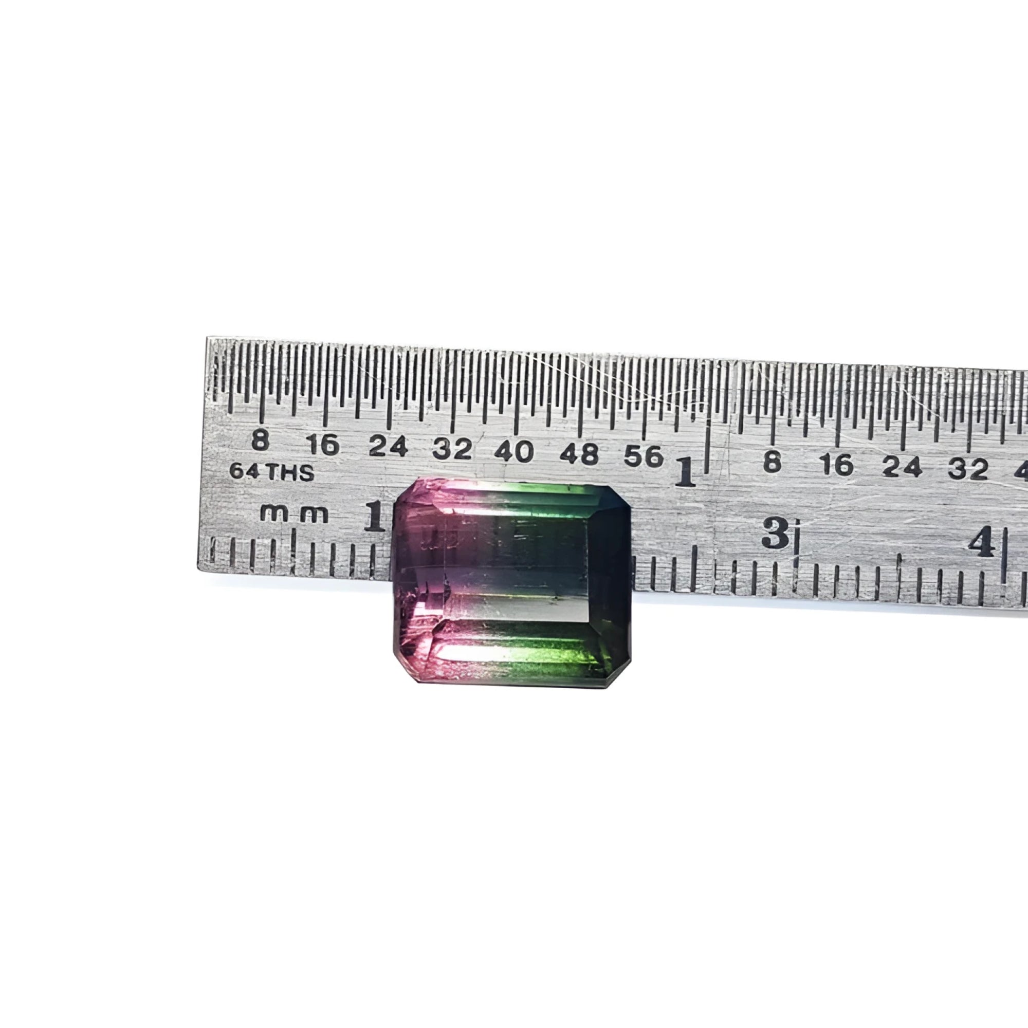Loose 6.55 ct. emerald-cut watermelon tourmaline, red to green, next to a ruler.