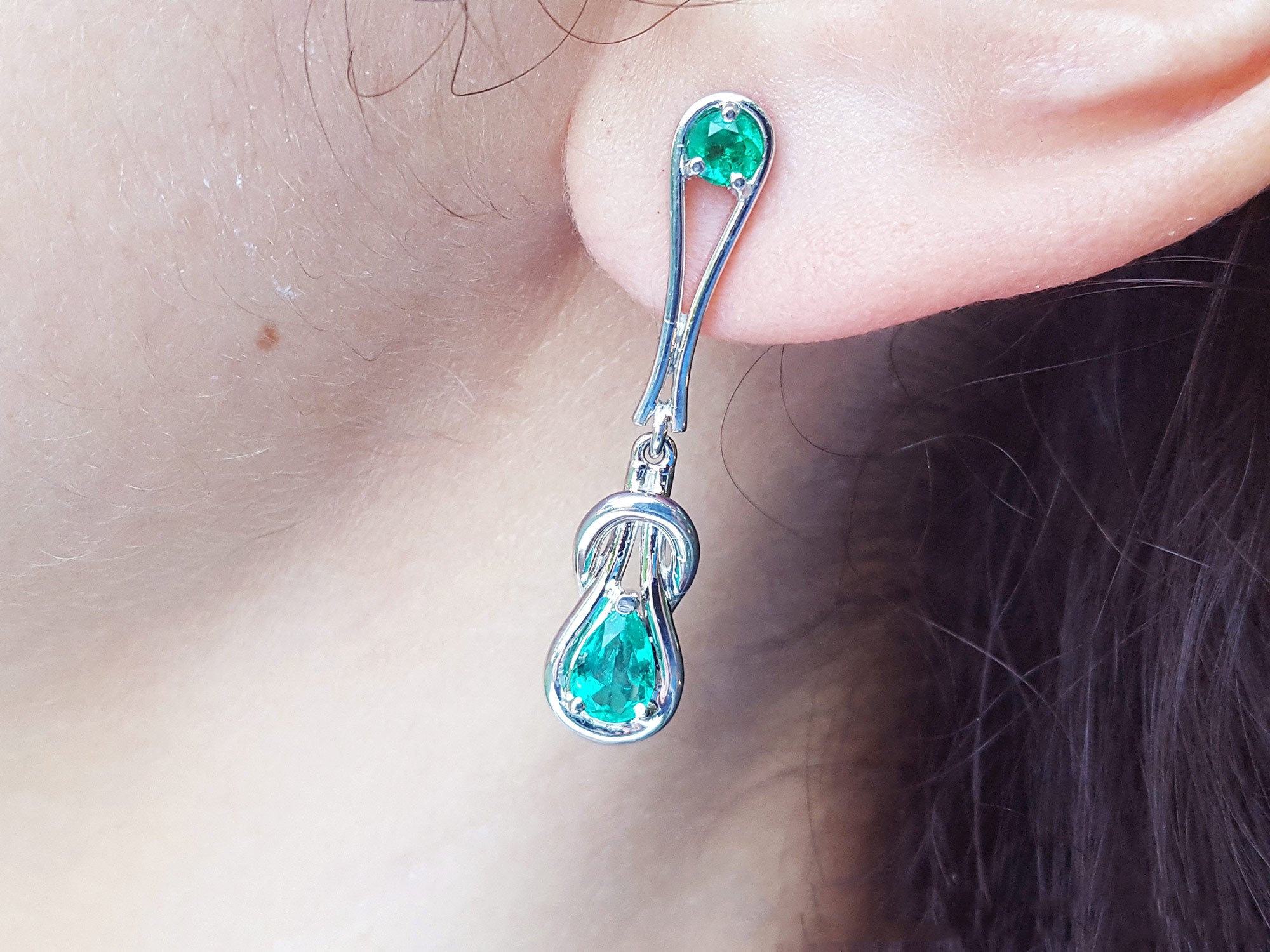 White gold with Love Knot Colombian emerald earring worn by a person