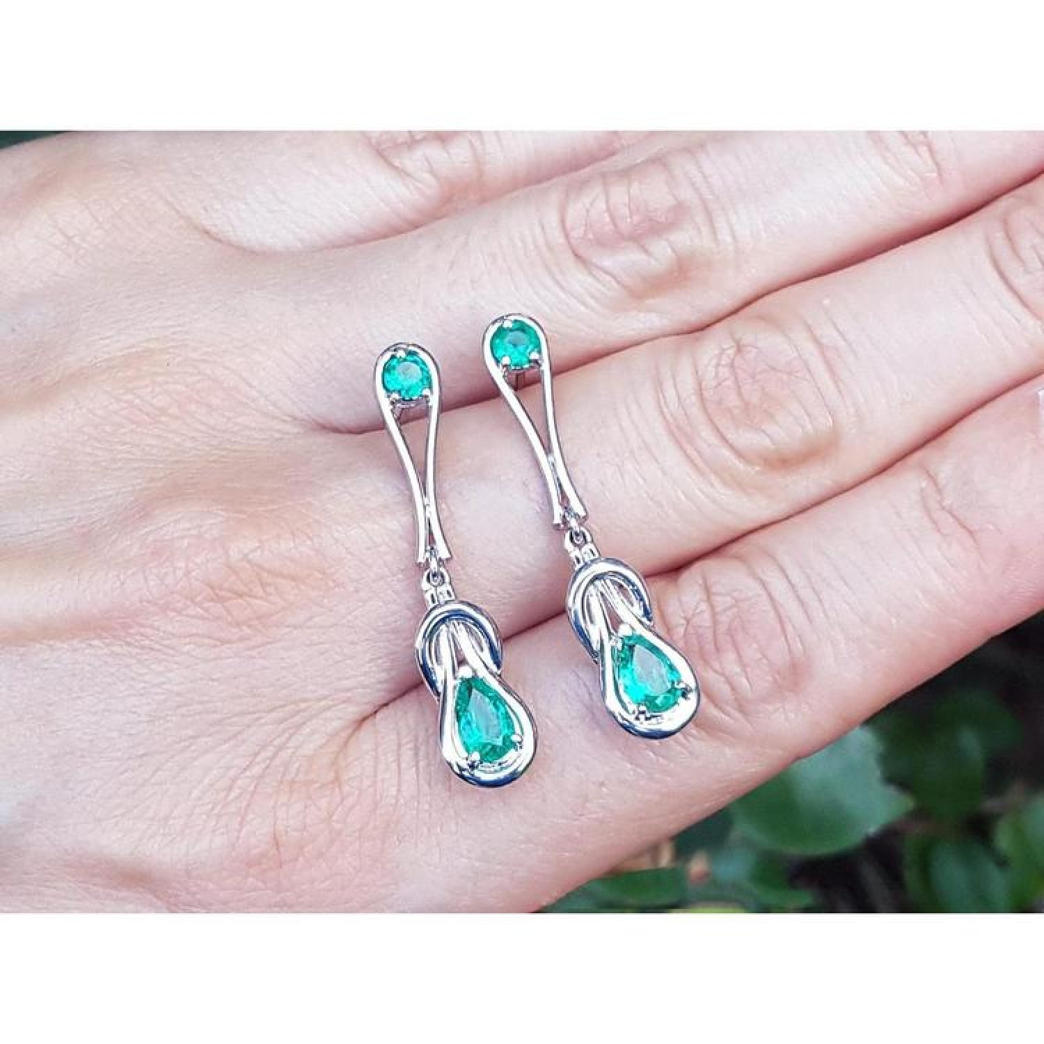 14K white gold love knot emerald earrings with pear-shaped Colombian emeralds.