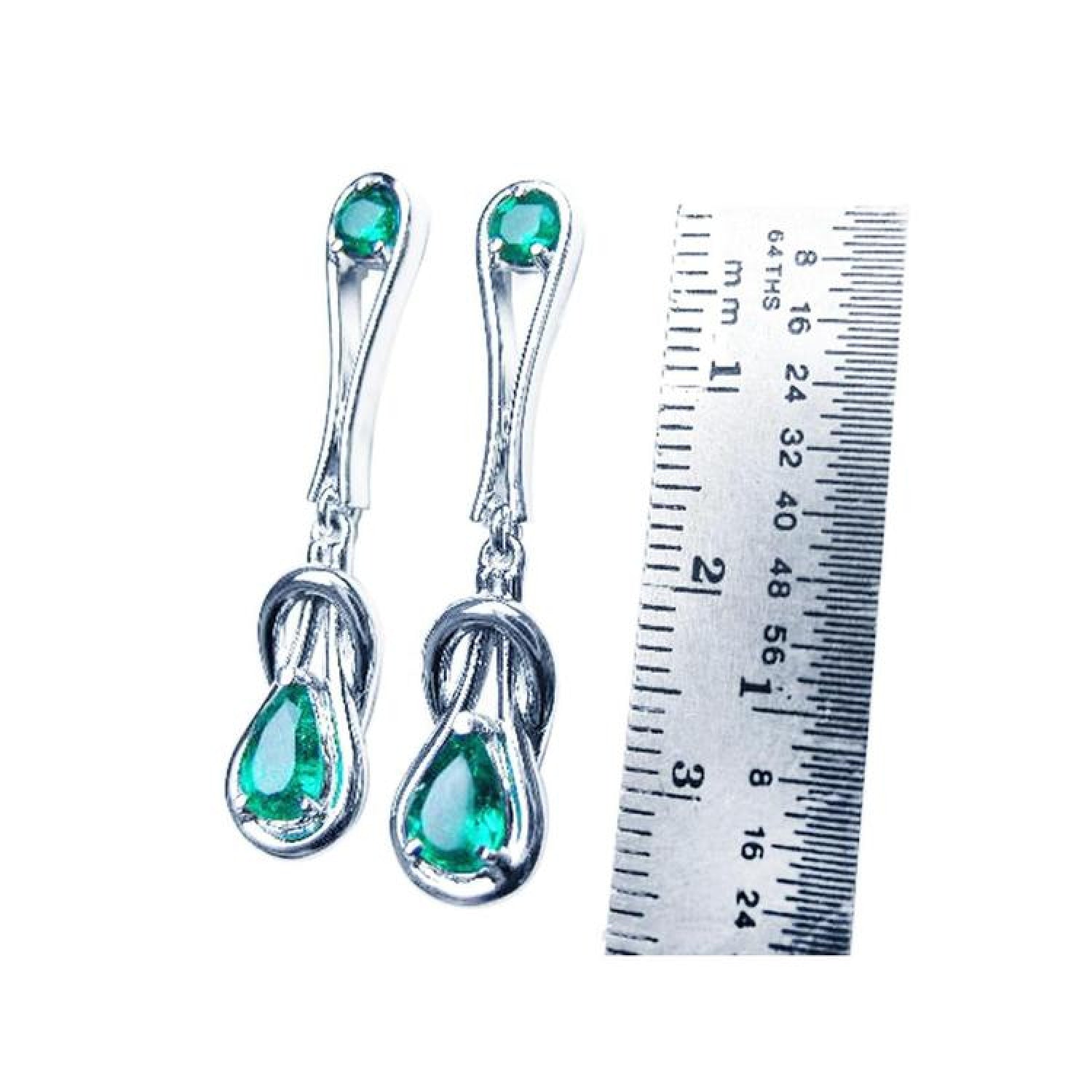 14K white gold love knot emerald earrings with pear-shaped Colombian emeralds, shown next to a ruler.