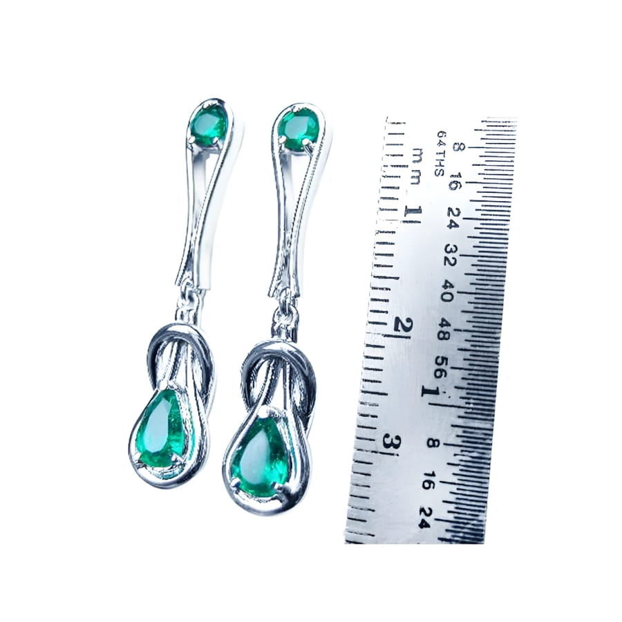 14K white gold love knot emerald earrings with pear-shaped Colombian emeralds, shown next to a ruler.