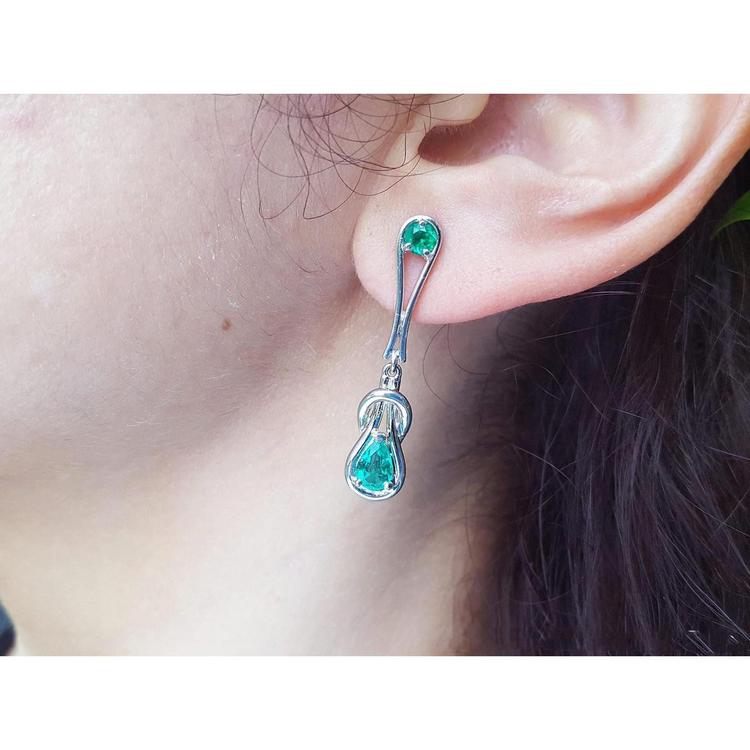 White gold Love Knot emerald earring worn by a person