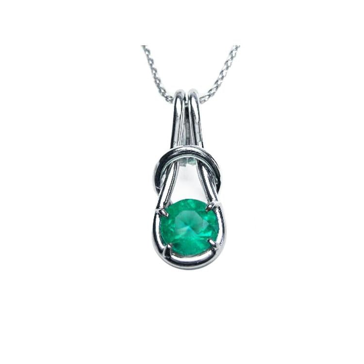 A white gold love knot pendant necklace with a round cut natural colombian emerald topside view.