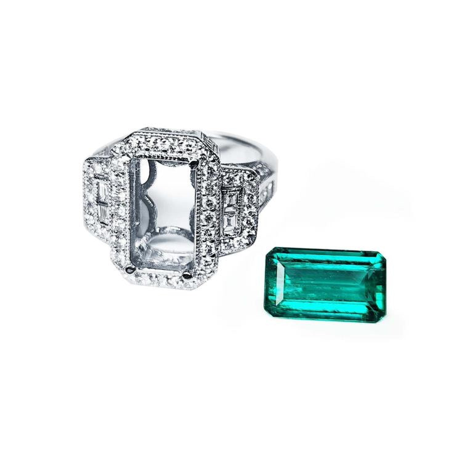 18K white gold diamond halo ring setting with baguette accents next to a vibrant emerald cut Colombian emerald.