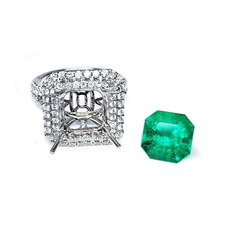 14K white gold diamond halo ring setting next to a loose, bright medium green Colombian emerald.