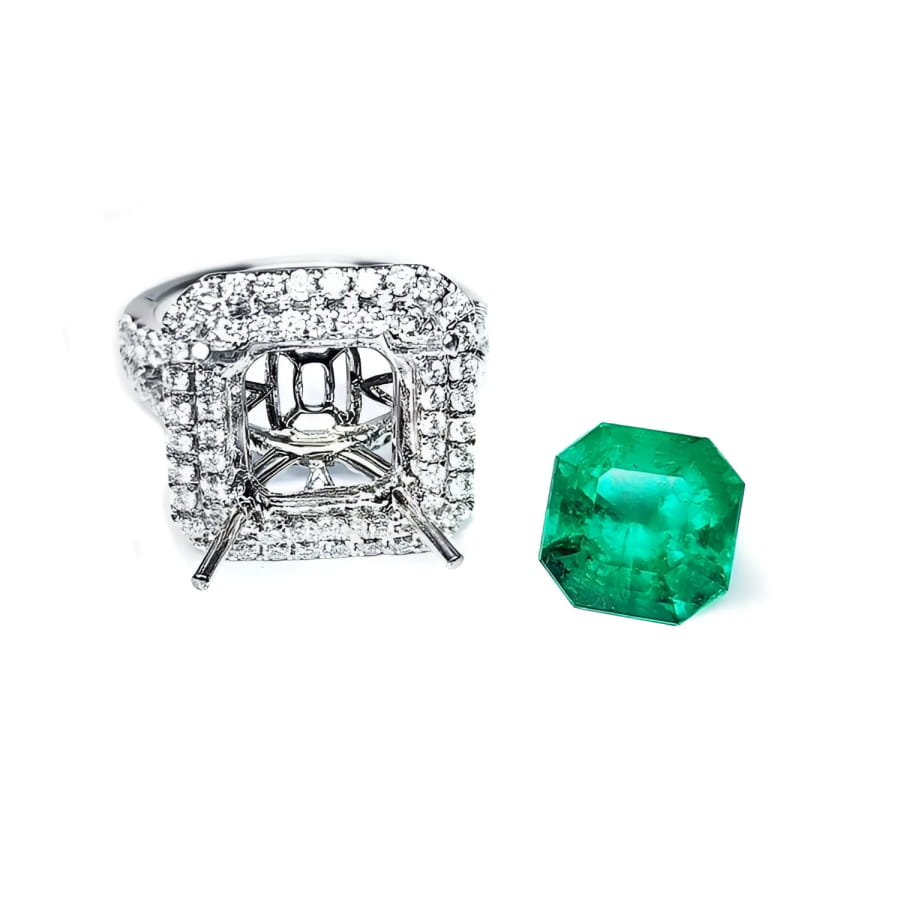 14K white gold diamond halo ring setting next to a loose, bright medium green Colombian emerald.
