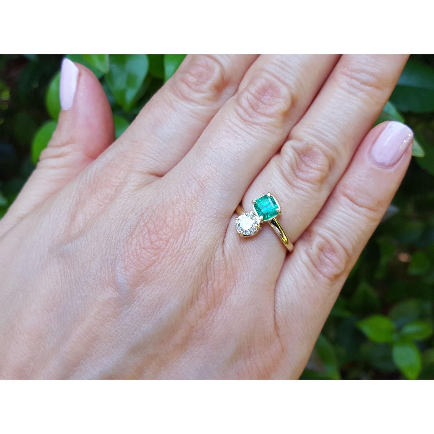 Natural colombian emerald and diamond two stone ring 18k yellow gold on a woman's hand.