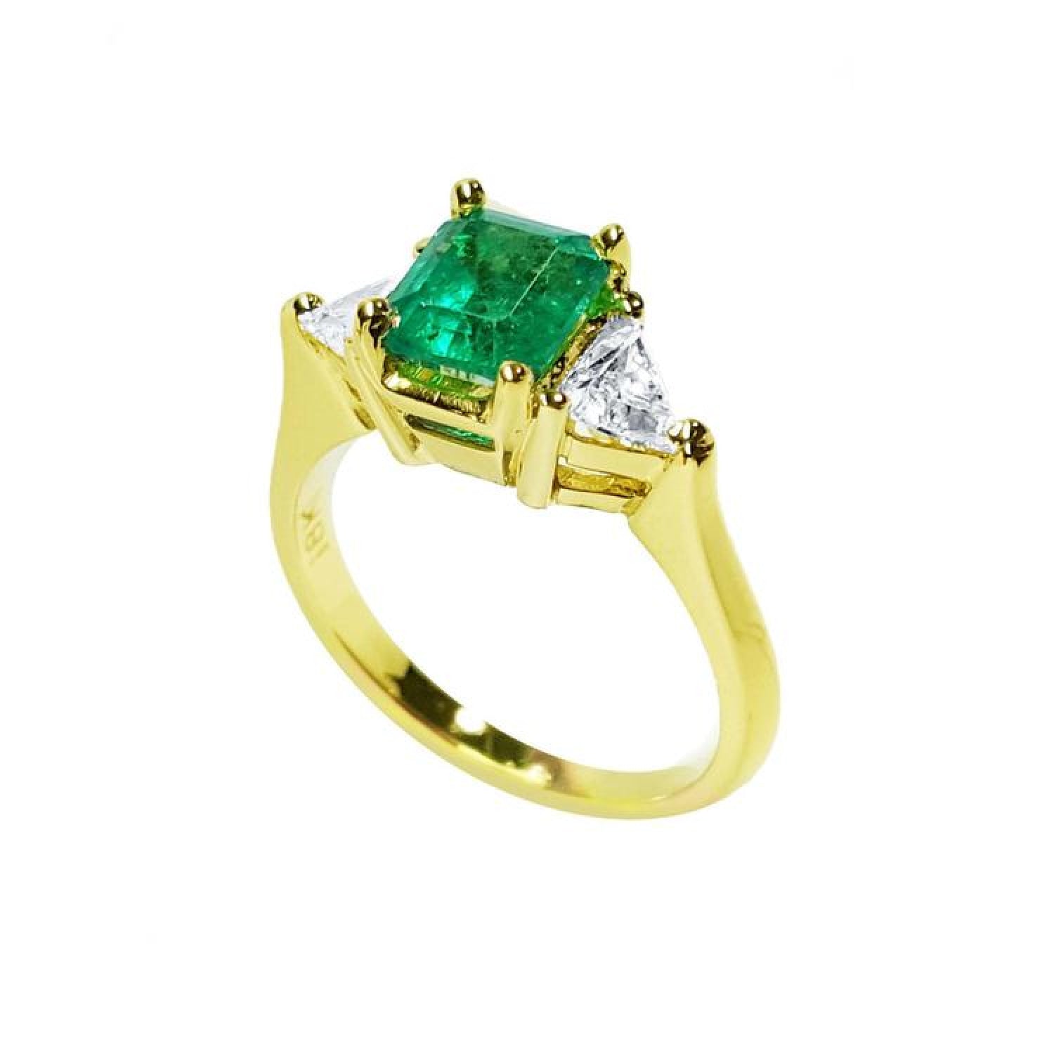 18K yellow gold three-stone ring with a vibrant emerald and two trillion-cut diamonds.