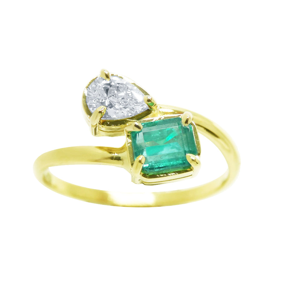A stunning You and Me Muzo emerald ring for women, paired with a natural pear-cut diamond, made of 18k yellow gold.