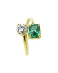 A 18k yellow gold ring featuring a round-cut diamond and a rectangular emerald-cut gemstone toi et moi design.